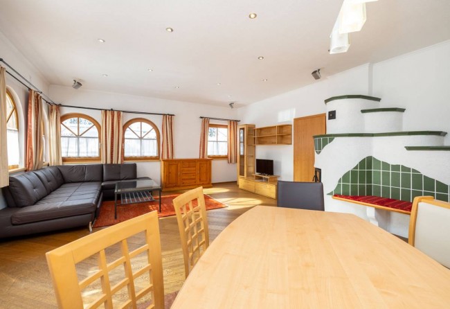 Wohnküche mit Essecke, Kachelofen, Couch und TV