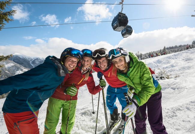 Freundesgruppe mit Gondelbahn Achterjet im Hintergrund © Flachau Tourismus